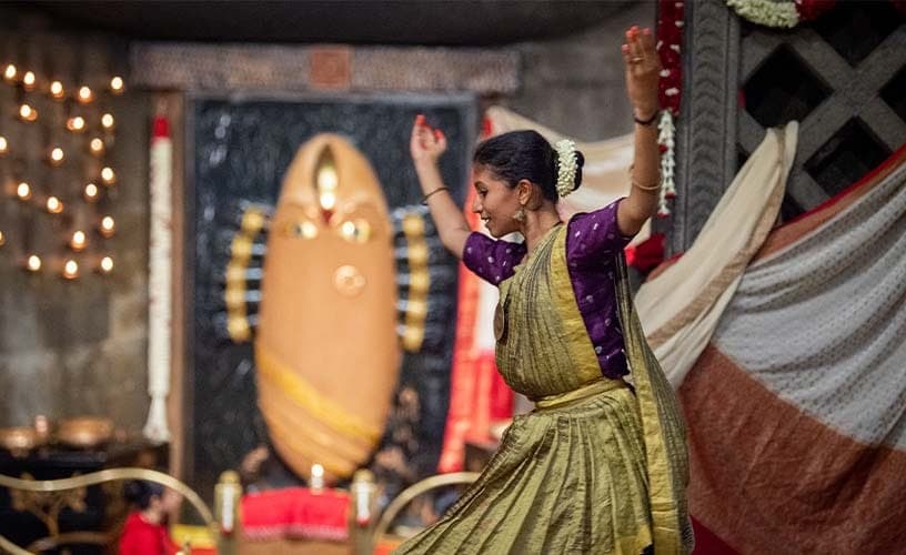 A dancer in a green sari before Linga Bhairavi adorned in cream