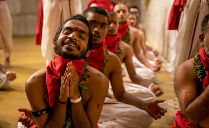 A devotee singing to the Devi with folded hands, eyes closed in joy