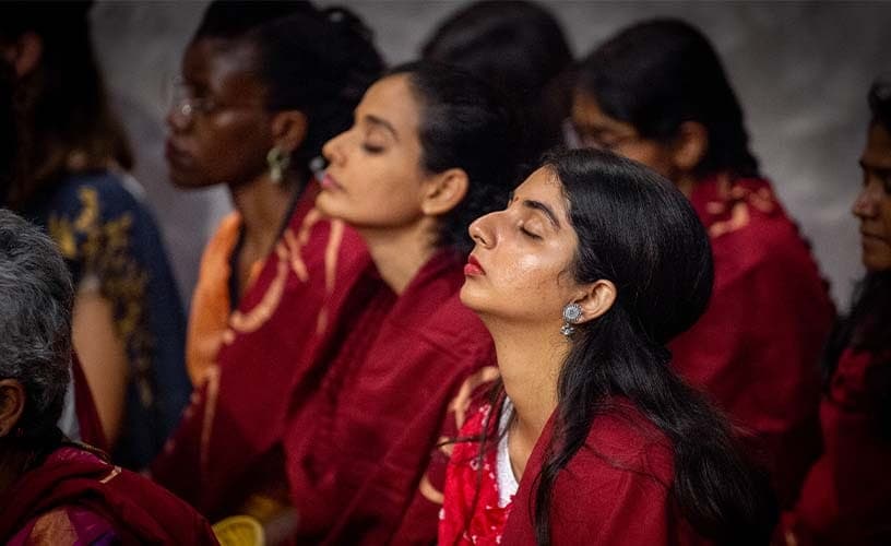 Devotees in red sitting with eyes closed, absorbed in sadhana at Linga Bhairavi during Navratri