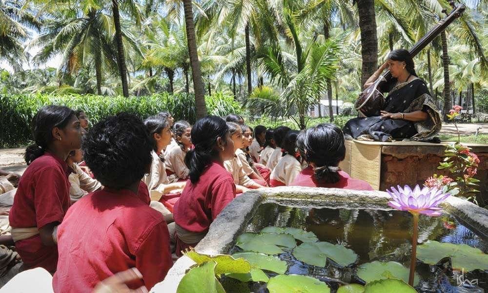Isha Samskriti students learning music with their teacher under the trees