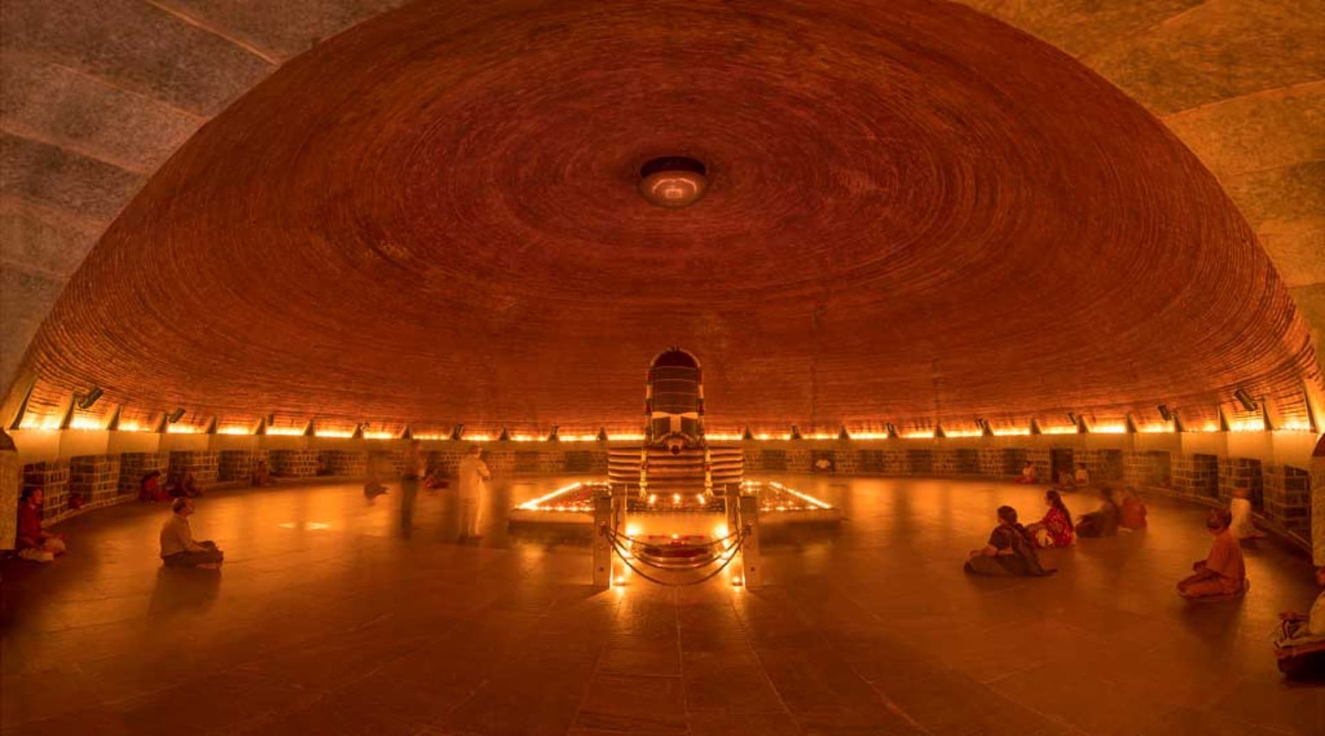 Interior of the Dhyanalinga meditation hall with warm lamp light