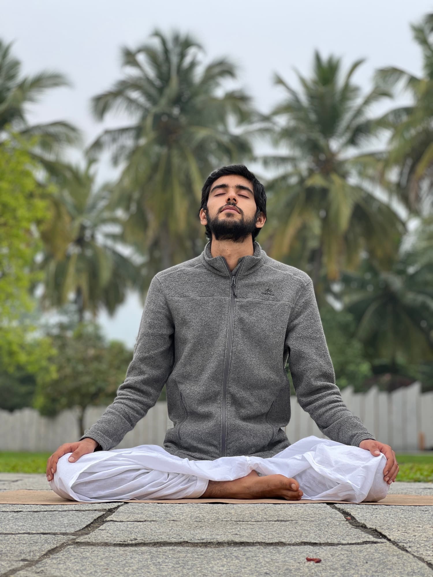 Quiet meditation on stone paving amid palms at the Yoga Center grounds