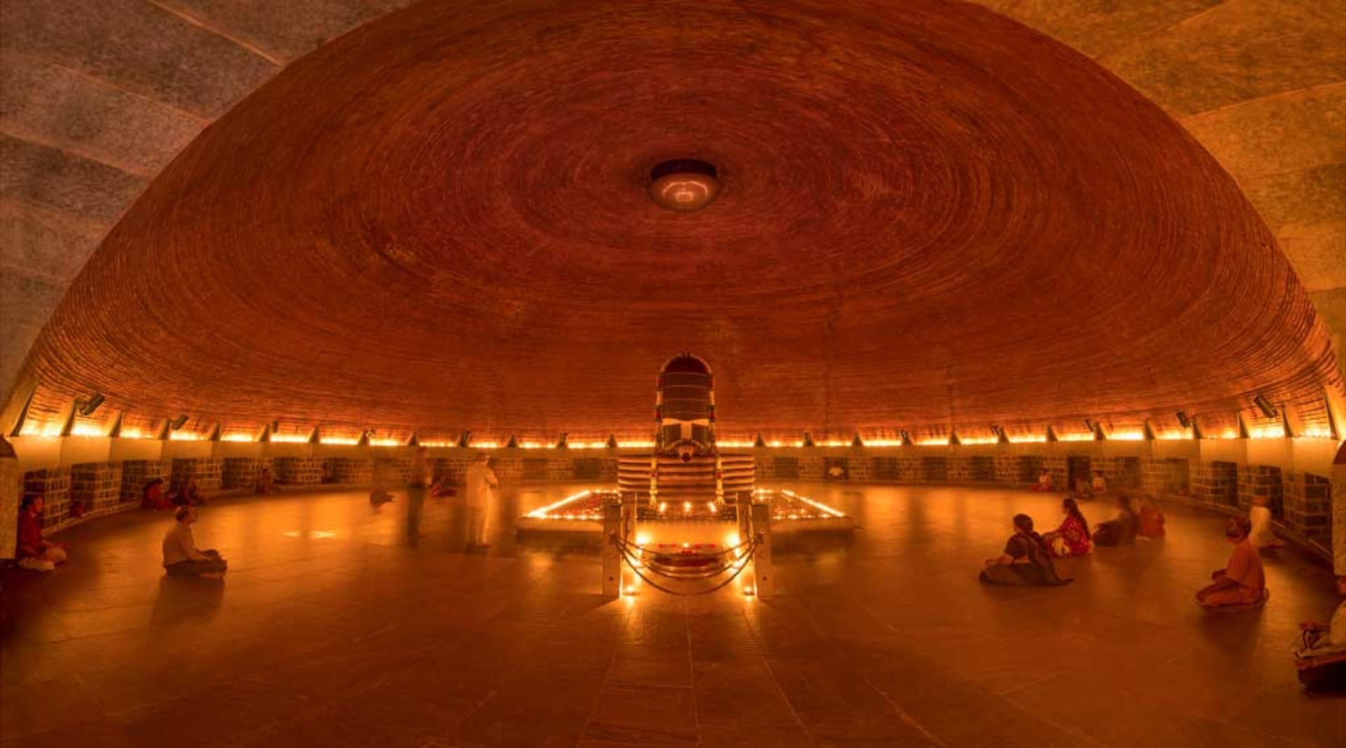 Interior of the Dhyanalinga meditation hall with warm lamp light