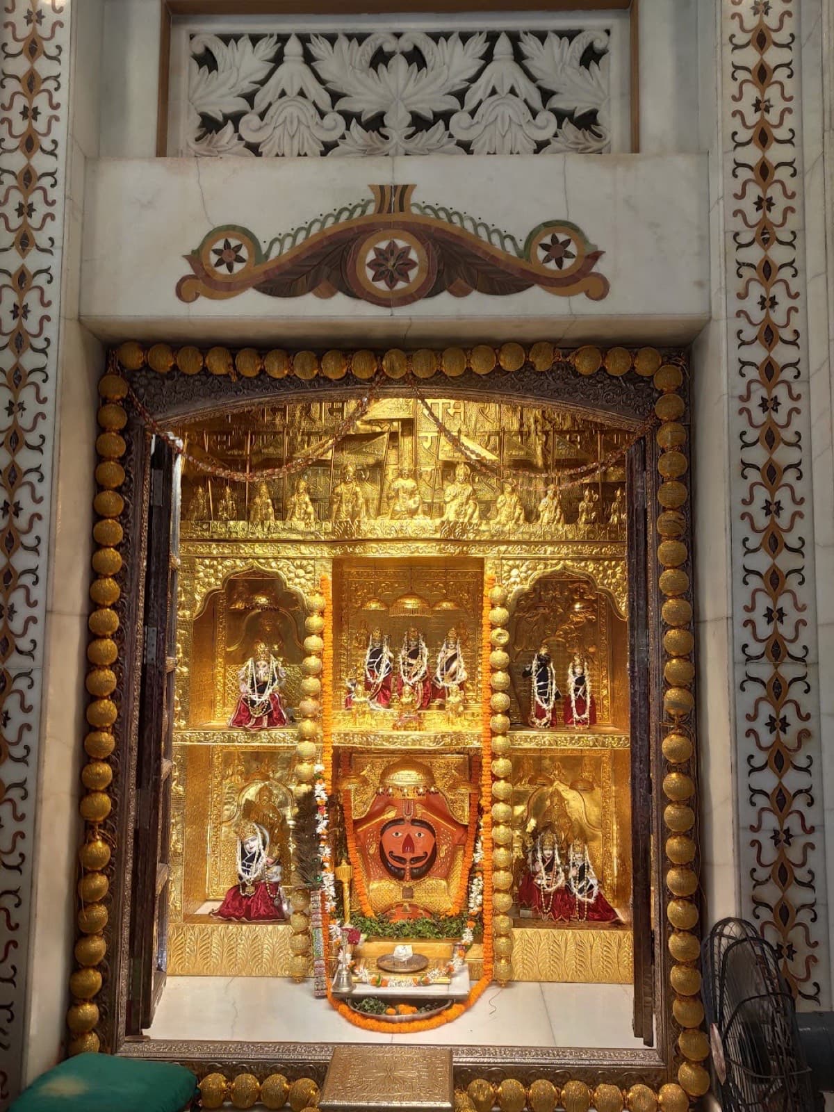 Gilded temple sanctum in Kashi with deities garlanded in marigolds