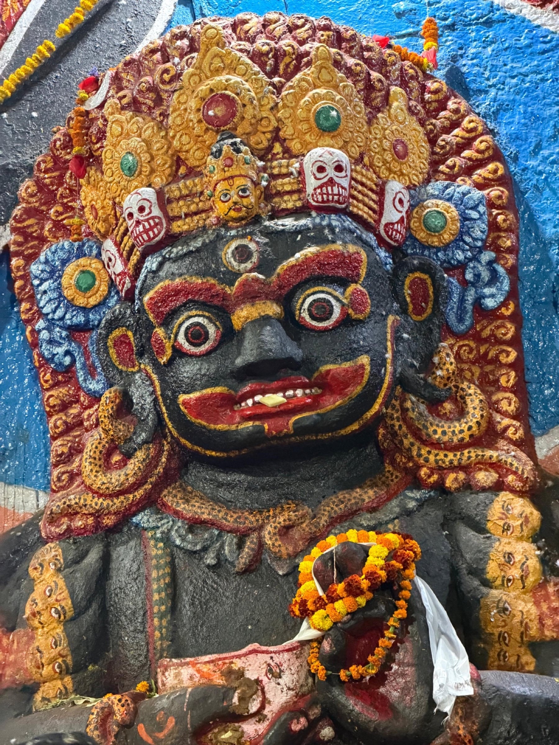 Close-up of the Kaal Bhairav relief sculpture in Kathmandu, Nepal, with marigold garlands